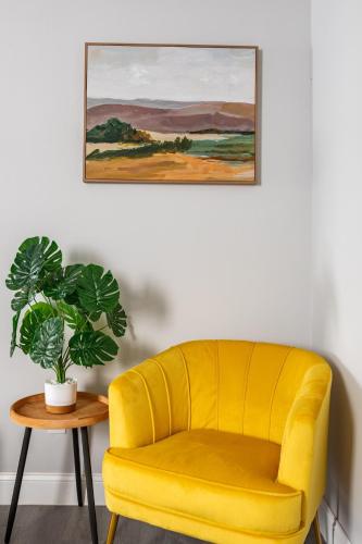 a yellow couch in a living room with a potted plant at Philly Getaway - Chic Stay Near Center City in Philadelphia