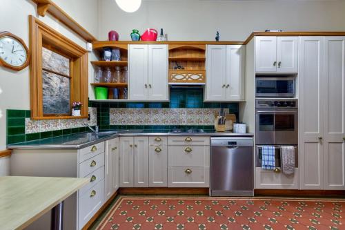 a kitchen with white cabinets and a clock on the wall at Stylish Victorian Home Near Walk to Beach & Te Papa in Wellington
