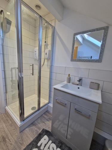 a bathroom with a shower and a sink and a mirror at Apartment 3 The Baileys Cwm in Cwm