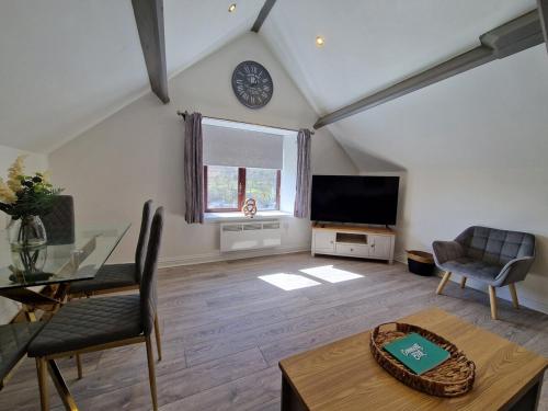 a living room with a table and a clock on the wall at Apartment 3 The Baileys Cwm in Cwm