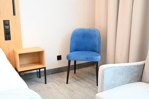 a blue chair sitting in a room next to a bed at Hotel Centrum Malbork in Malbork