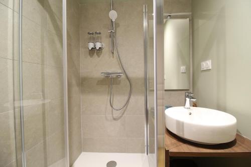 La salle de bains est pourvue d'une douche et d'un lavabo blanc. dans l'établissement LES CARMES-Climatisation-Confort-WiFi-Hypercentre-Netflix, à Avignon