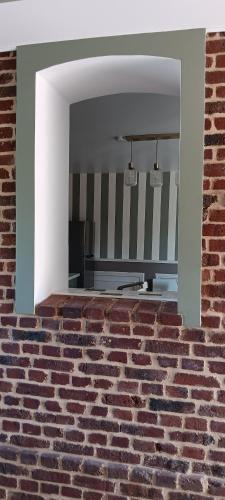 - un mur en briques avec une fenêtre dans la chambre dans l'établissement Gîte la pause picarde, à Franleu