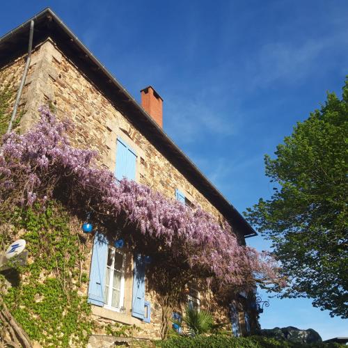 un bâtiment avec des fleurs violettes sur son côté dans l'établissement chambre dhote condat sur ganaveix, à Condat-sur-Ganaveix