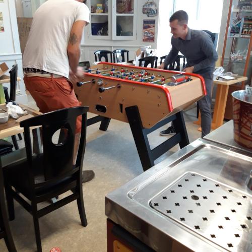 deux hommes travaillent sur une table de baby-foot dans l'établissement chambre dhote condat sur ganaveix, à Condat-sur-Ganaveix