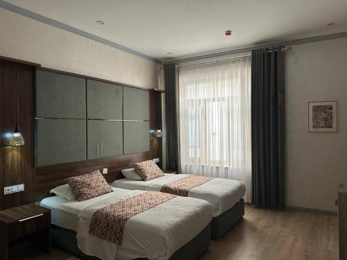 una camera d'albergo con due letti e una finestra di Atrium Hotel a Bukhara