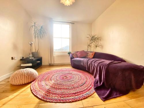 a living room with a purple couch and a large rug at London's Central East End 2 Bedroom City Apartments in London