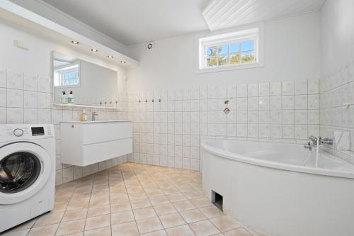 a white bathroom with a tub and a washing machine at Stort hus med 7 soverom på Eik in Tønsberg