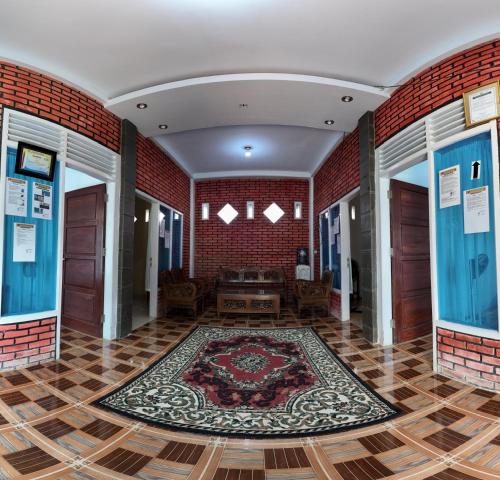 a room with a rug on the floor and a brick wall at Zico Homestay in Andalas