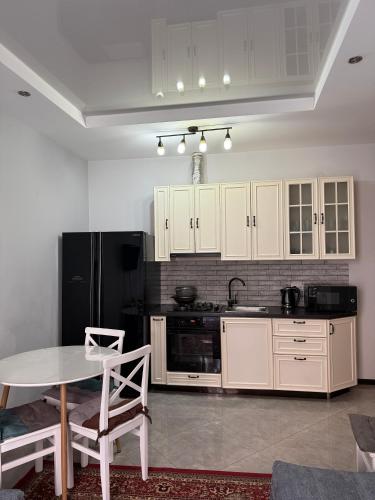 a kitchen with a table and a black refrigerator at Cozy Apartment In Ortacahala in Tbilisi City