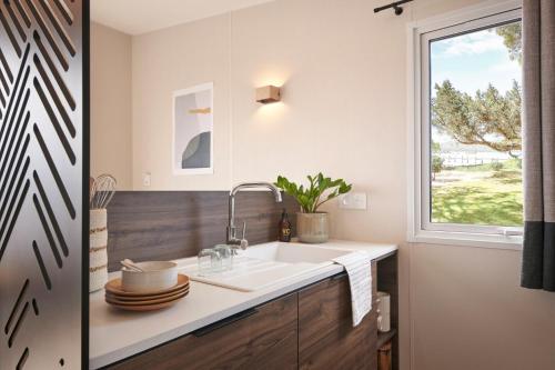 une cuisine avec un évier et une fenêtre dans l'établissement Camping maeva Escapades Bel Air, à Sadirac