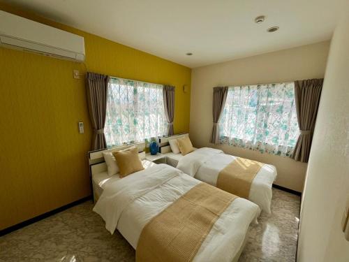 two beds in a room with yellow walls and windows at Sunrise terrace kintown in Kin