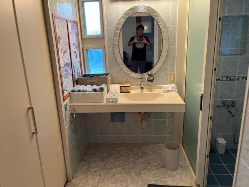 a man taking a picture of a bathroom with a sink at Sunrise terrace kintown in Kin