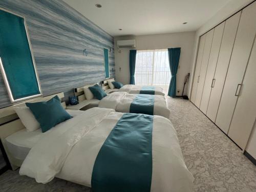 a hotel room with four beds with blue pillows at Sunrise terrace kintown in Kin