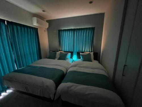 two beds in a room with blue curtains at Sunrise terrace kintown in Kin