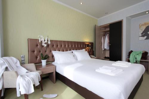 Un dormitorio con una gran cama blanca y una silla. en Athens Lotus Hotel, en Atenas
