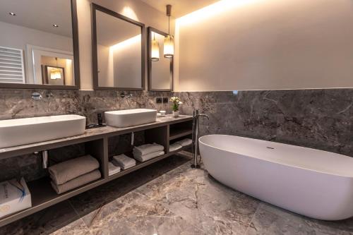 a bathroom with two sinks and a tub and mirrors at Park Hotel Imperial in Limone sul Garda