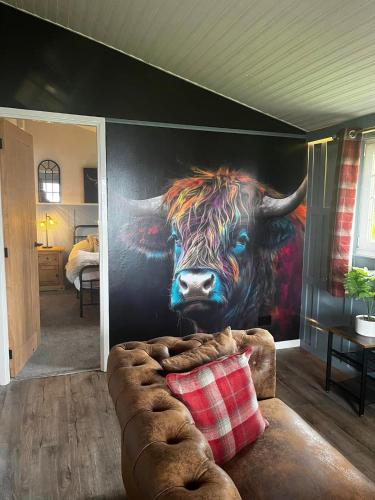 a mural of a cow on a wall in a room at Appin Holiday Homes -Caravans, Lodges, Shepherds Hut and Train Carriage stays in Appin