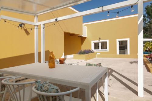 a patio with a table and chairs and a yellow house at Casa Amarela - Countryside Villa in Alcobaça