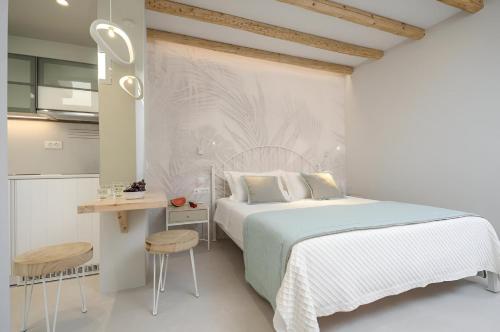 a white bedroom with a bed and a kitchen at Antony Suites (Adults Only) in Naxos Chora