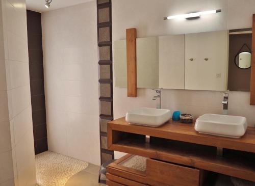 un bagno con 2 lavandini bianchi e uno specchio di Villa Reve d Azur a Saint-Leu