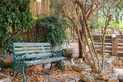 a green park bench sitting next to a tree at Country lodging in Manot in Manot