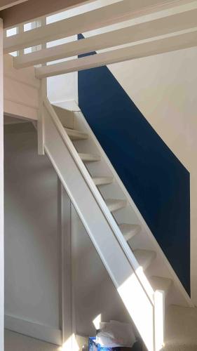 - un escalier blanc dans une chambre avec un mur bleu dans l'établissement Duplex avec terrasse à 10 minutes à pied de la plage, à Villers-sur-Mer