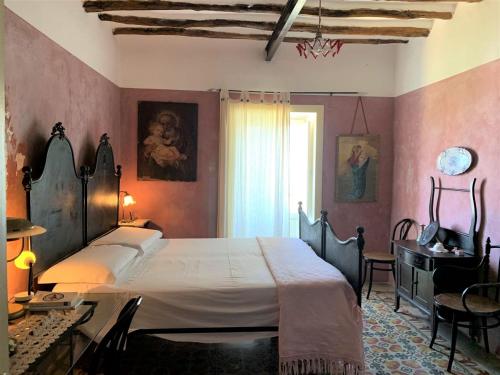 a bedroom with a bed and a table and a desk at Casa Pomelia - in centro a Malfa in Malfa