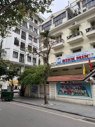 a building with a tree on the side of a street at Studio 2 Byhomelinh Phố Cổ Hoàn Kiếm in Hanoi