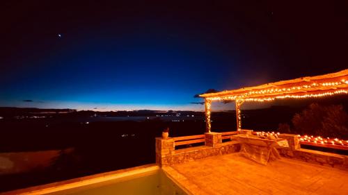 a deck with a pergola with lights on it at night at Cassiopea Guest House Evia Greece in Nerotriviá