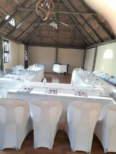 a large room with white tables and white chairs at Dream Catcher Hotel in Gaborone