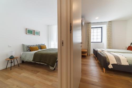 a room with two beds and a bedroom with a bed sqor at The Green Tiles Apartment incl Parking by Home Sweet Home Aveiro in Aveiro