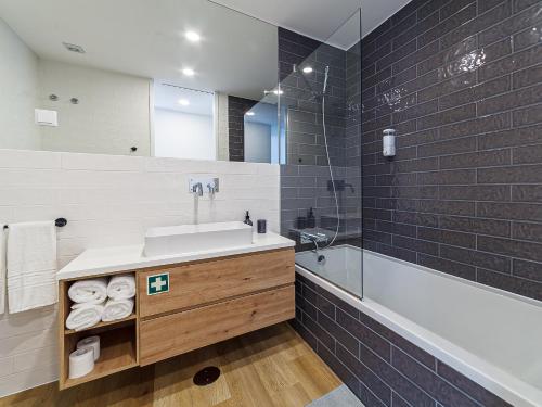 a bathroom with a sink and a tub and a mirror at The Green Tiles Apartment incl Parking by Home Sweet Home Aveiro in Aveiro