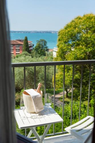 a table with wine glasses and a book on a balcony at Hotel Villa Maria in Sirmione