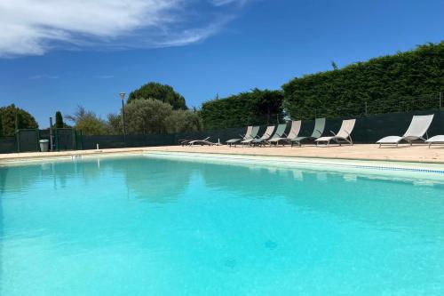 a large swimming pool with chairs and blue water at 04B4 Beautiful studio in a mas provençal - pool in Brunet