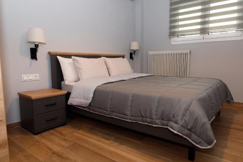 a bedroom with a bed with a night stand and a window at Bebis House in Prosílion