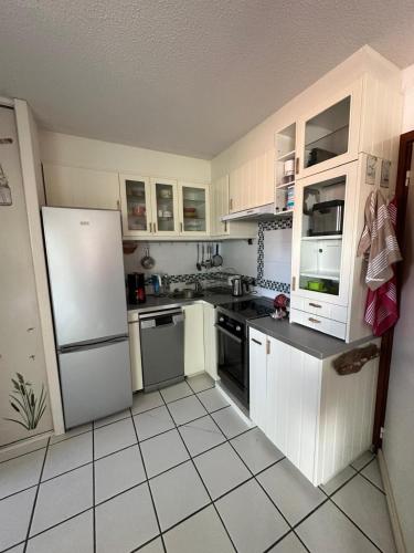 une cuisine avec des armoires blanches et un réfrigérateur blanc dans l'établissement Studio centre-ville, à Capbreton