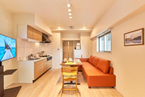 a living room with an orange couch and a kitchen at Nomadland Shinagawa Omori 1004 in Tokyo