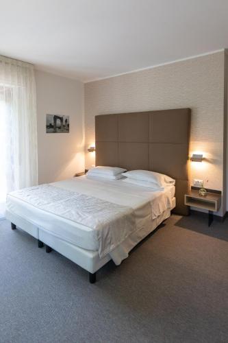 a bedroom with a large white bed with two lamps at Hotel Villa Maria in Sirmione