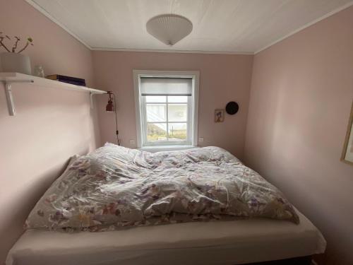 a bedroom with a bed with a comforter and a window at Cosy house with stunning view in Sørvágur