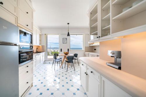 une cuisine avec des armoires blanches et une table avec des chaises dans l'établissement Appartement vue mer panoramique, à Cannes