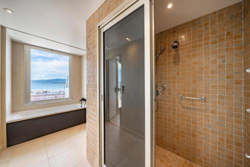 La salle de bains est pourvue d'une douche à l'italienne à côté d'une fenêtre. dans l'établissement Appartement vue mer panoramique, à Cannes
