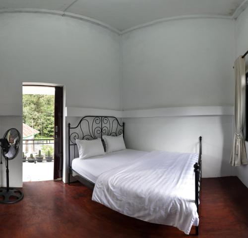 a white bedroom with a large bed with white sheets at Zico Homestay in Andalas