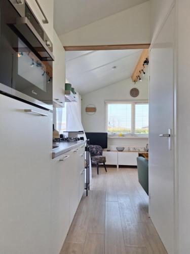 a kitchen with white appliances and a living room at Rekerlanden 267 in Warmenhuizen