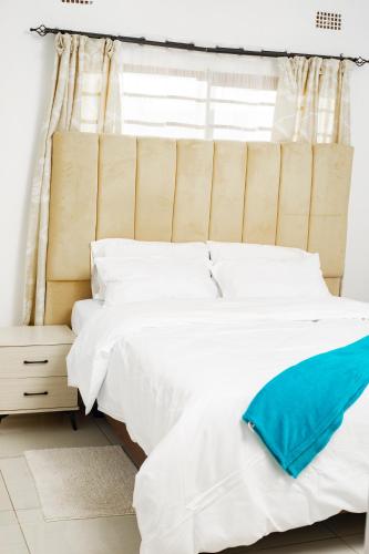 a bed with white sheets and a blue pillow on it at Luya's Place in Lusaka