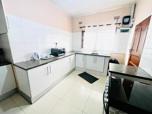 a kitchen with white cabinets and a black counter top at Luya's Place in Lusaka