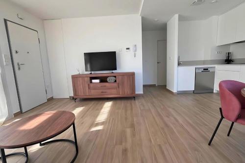 a living room with a television and a table and chairs at Golf sun and a private pool for a dream holiday! in Orihuela