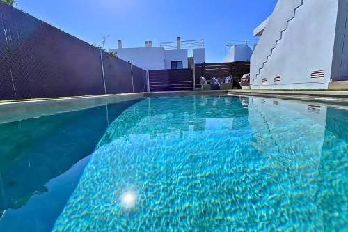 a swimming pool with blue water in front of a fence at Golf sun and a private pool for a dream holiday! in Orihuela