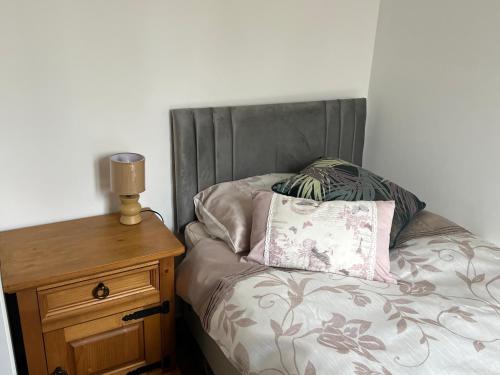 a bed with a pillow and a wooden night stand at Chez Casa in Sourdeval