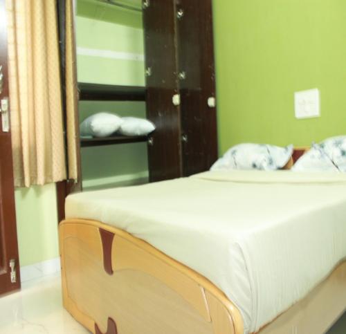 a bed in a room with a green wall at Kalyan Residency By Azalea in Madurai